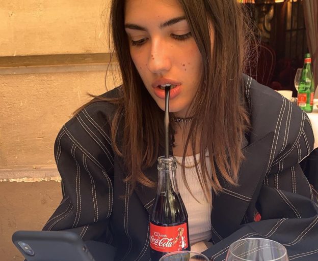 woman sipping soda and looking at her phone
