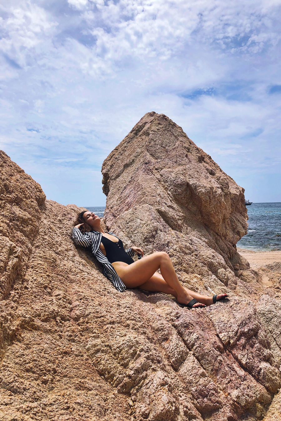 woman posing on rock on beach wearing swimsuit
