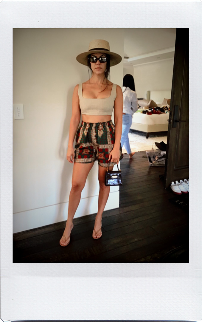 Kourtney Kardashian wearing printed shorts and hat