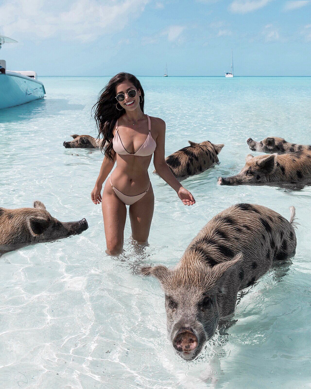 Nicole Isaacs stands in the ocean with pigs.