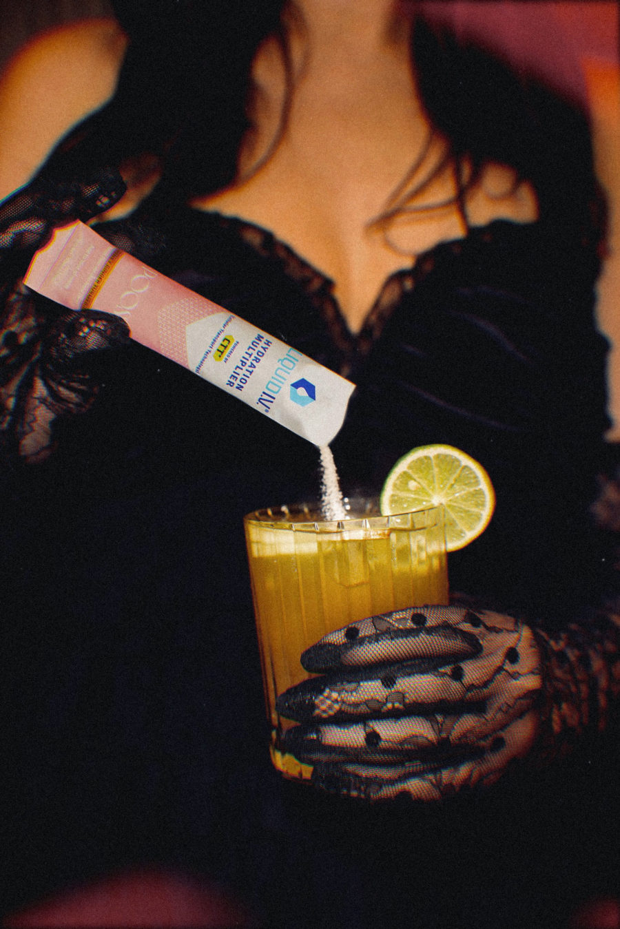woman wearing black gloves holdingpoosh liquid iv ginger marg