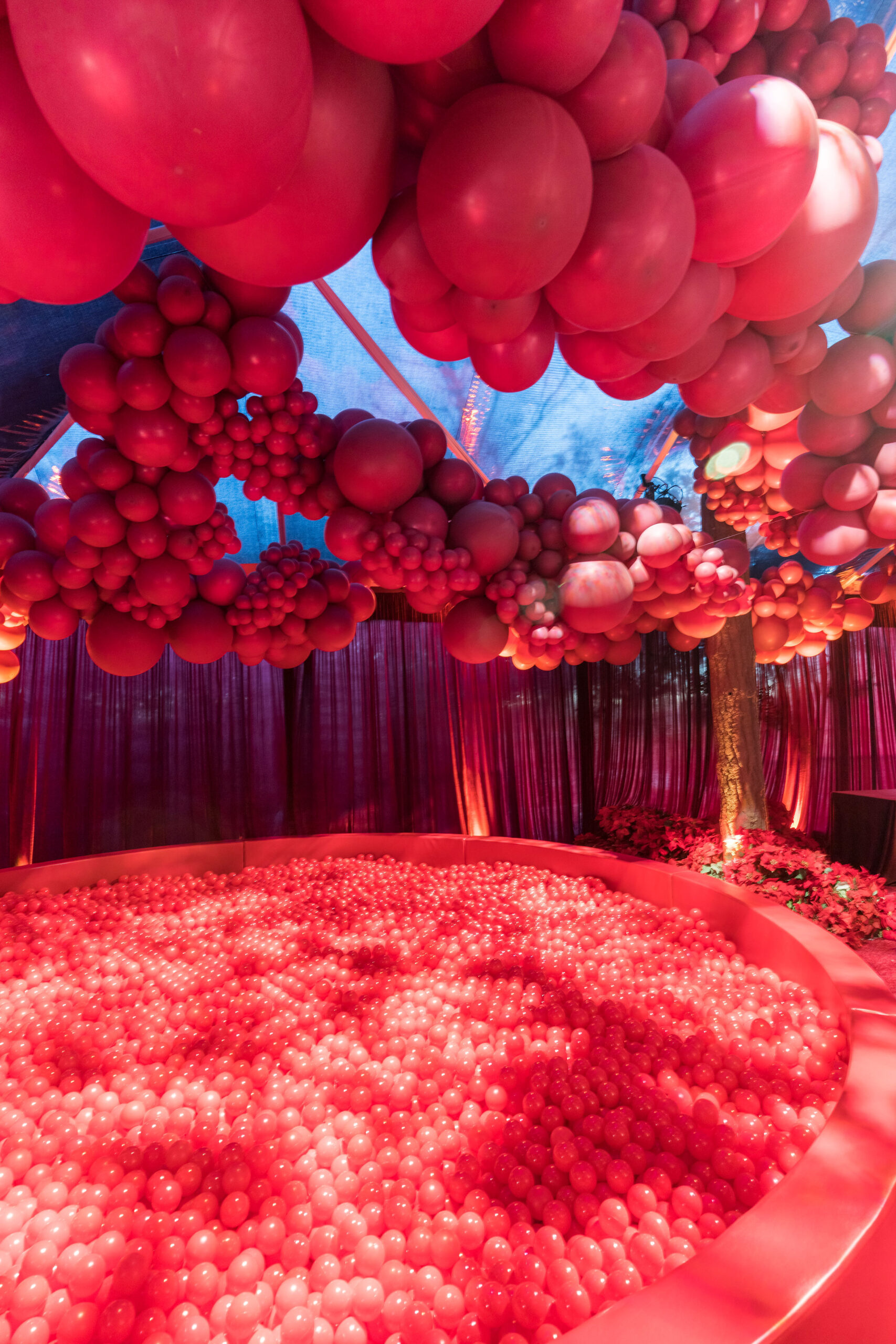 Red ball pit under red balloons on the ceiling at Kourtney Kardashian Barker Christmas Eve 2022 party