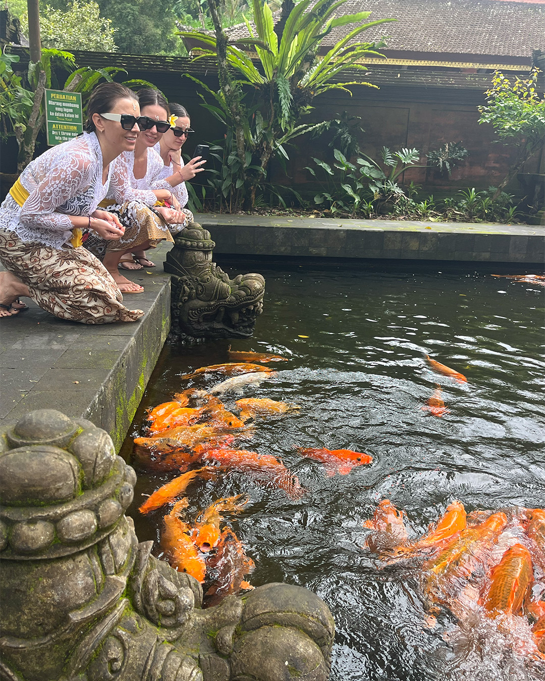 Joyful women looking at Koi fishes in pond