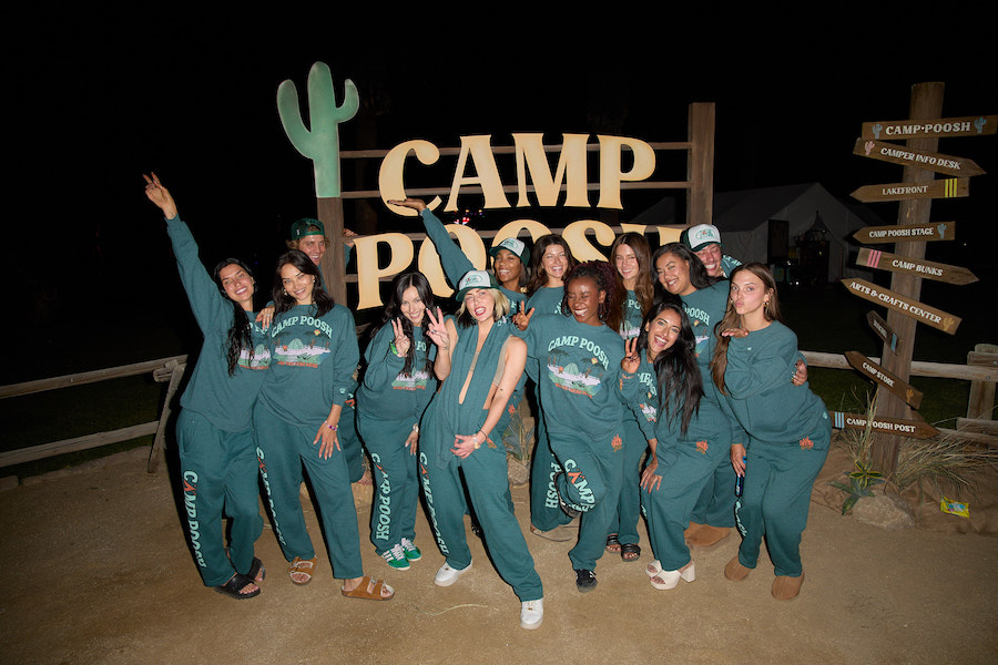 The camper wearing matching sweats outside the camp poosh sign at night